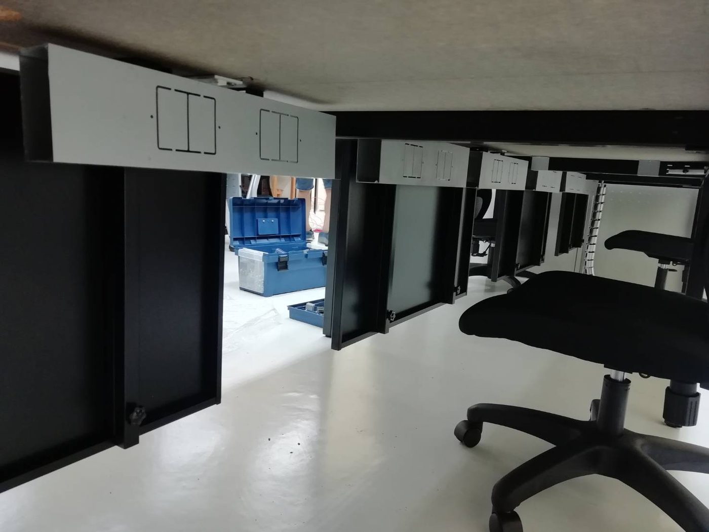 黑腳工作桌桌下一支銀色鋁製走線槽，側面有插座開孔