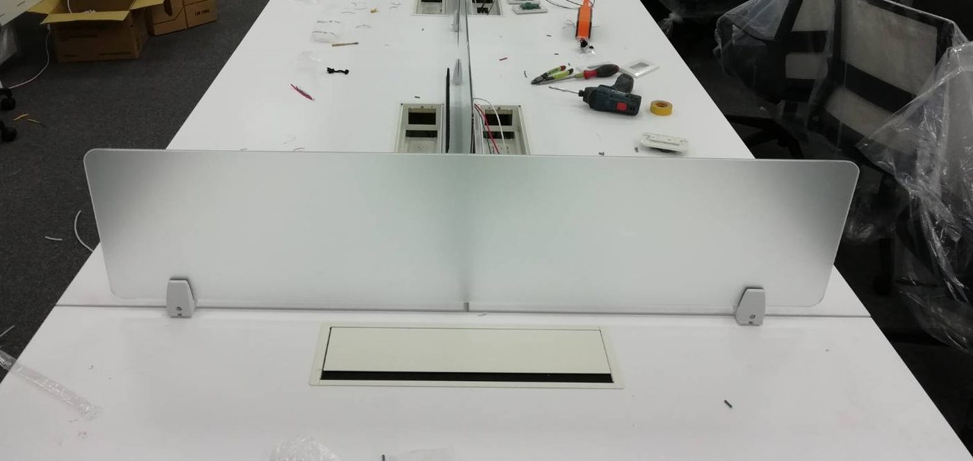 白色長桌中間立一片霧面玻璃桌屏，下方有兩顆銀色夾具，桌面有一組嵌入式線盒