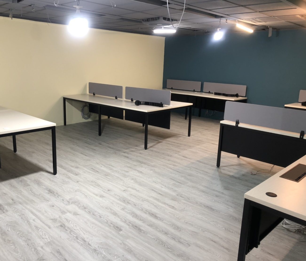 白色桌面黑色桌腳的工作站桌，桌面立灰色桌屏，對坐排列